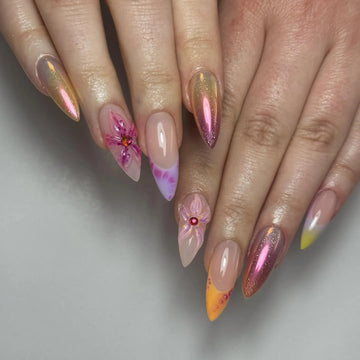 Hand with iridescent sunset chrome pink press-on nails and 3D floral accents