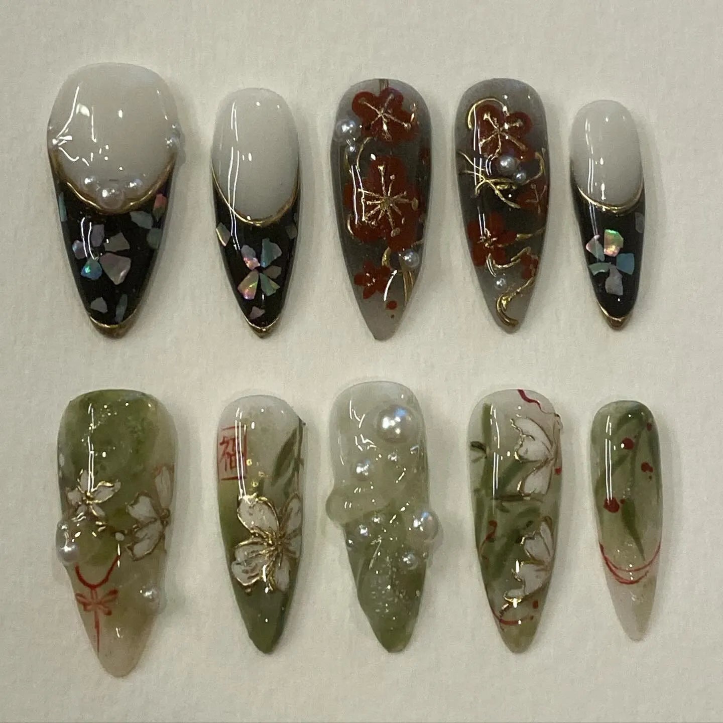 Handmade Japanese floral press-on nails with gold foil, pearl accents, and plum blossom designs.