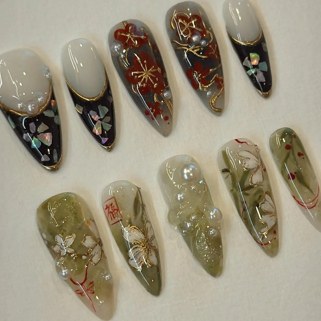 Handmade Japanese floral press-on nails with gold foil, pearl accents, and plum blossom designs.