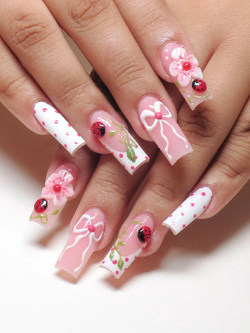 Handmade press-on nails with 3D ladybug, pink floral, white bow, and polka dot designs.
