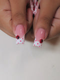 Handmade pink and white polka dot press-on nails with 3D ladybug accents