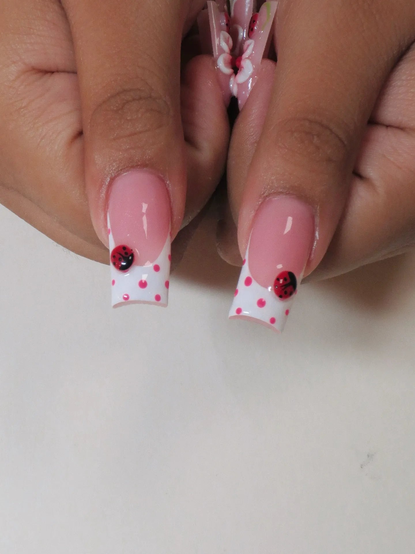 Handmade pink and white polka dot press-on nails with 3D ladybug accents