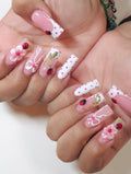 Handmade press-on nails with pink and white polka dots, 3D floral, bow, and ladybug art.
