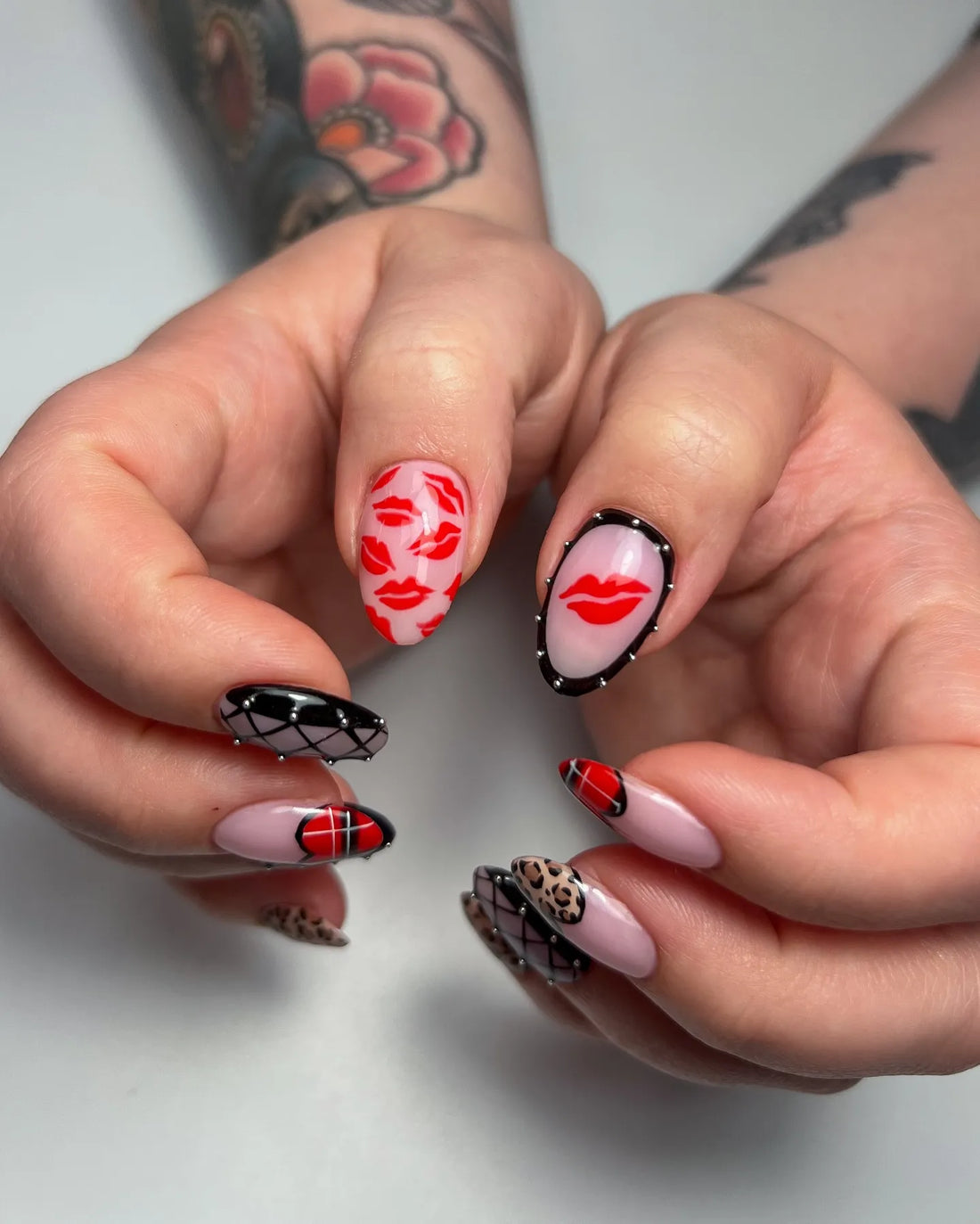 Handmade press-on nails with leopard print, red plaid hearts, black gothic studs, and French tips.