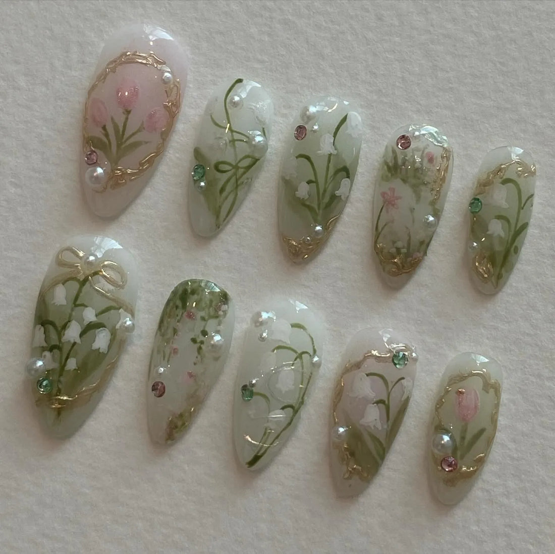 Handmade press-on nails with lily of the valley, tulip, pearl, and gold spring floral designs