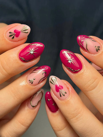 Handmade magenta press-on nails with pink heart accents, gold filigree, and starburst designs
