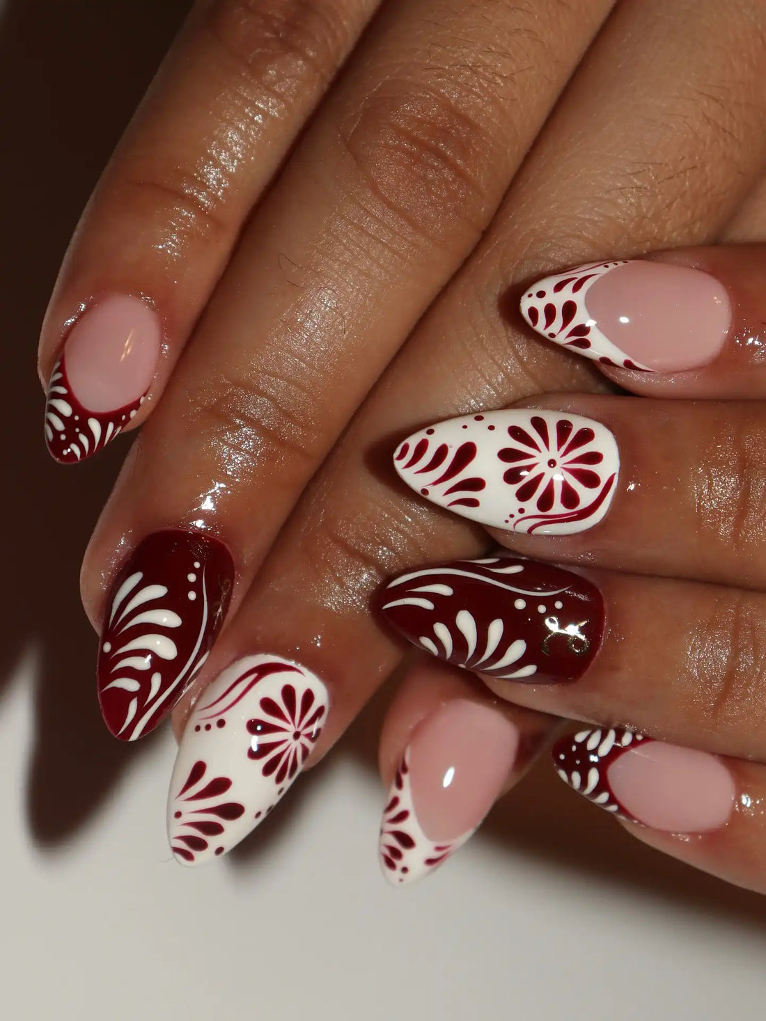 Handmade maroon and white press-on nails with folk art floral festive patterns