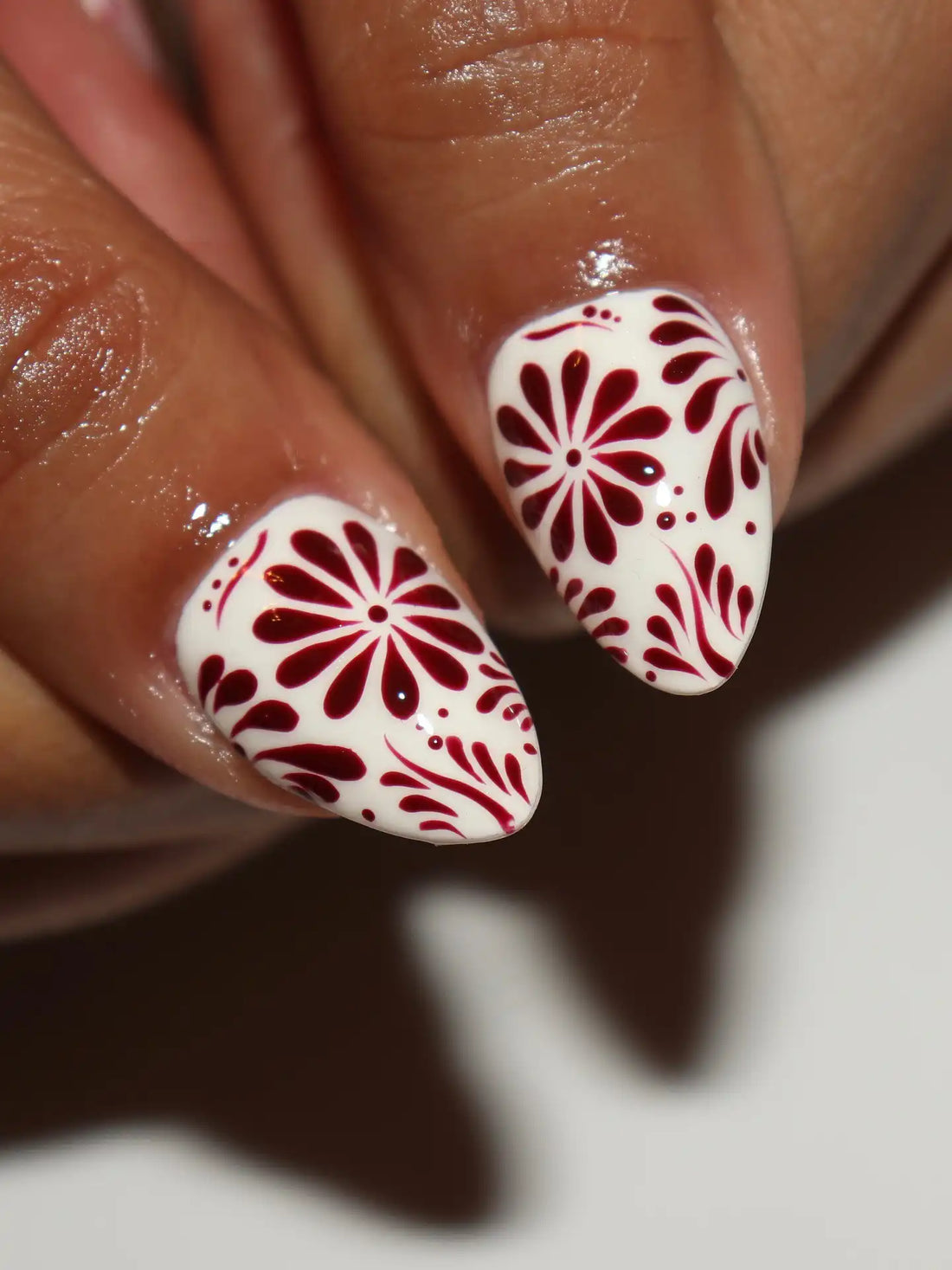 Handmade maroon and white press-on nails with folk art floral festive patterns