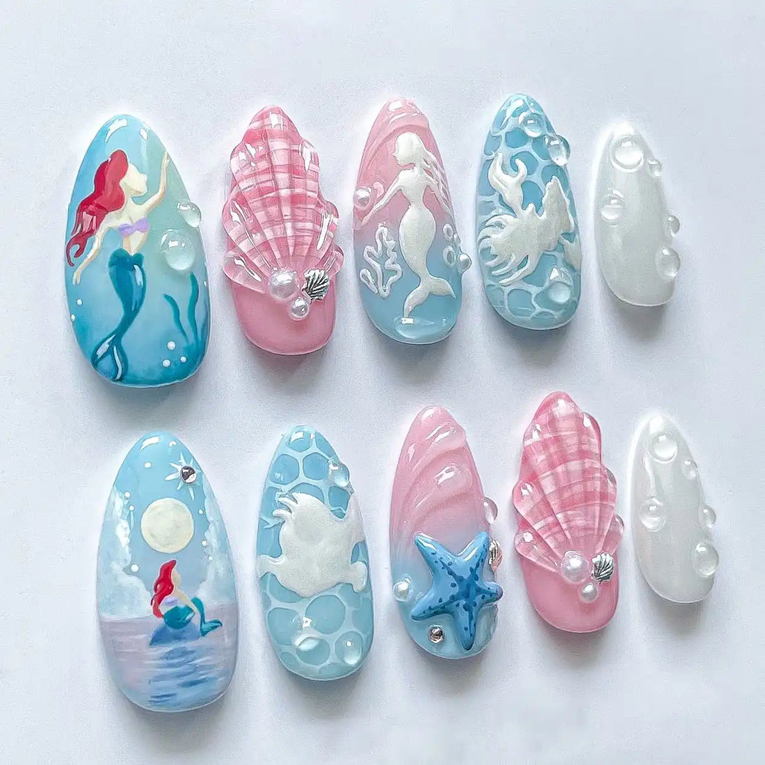Handmade mermaid themed press-on nails with pink, blue, sea shell and ocean fantasy designs.