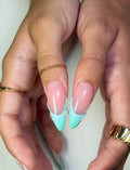 Hand with long mint and seafoam French tip press-on nails, glossy finish