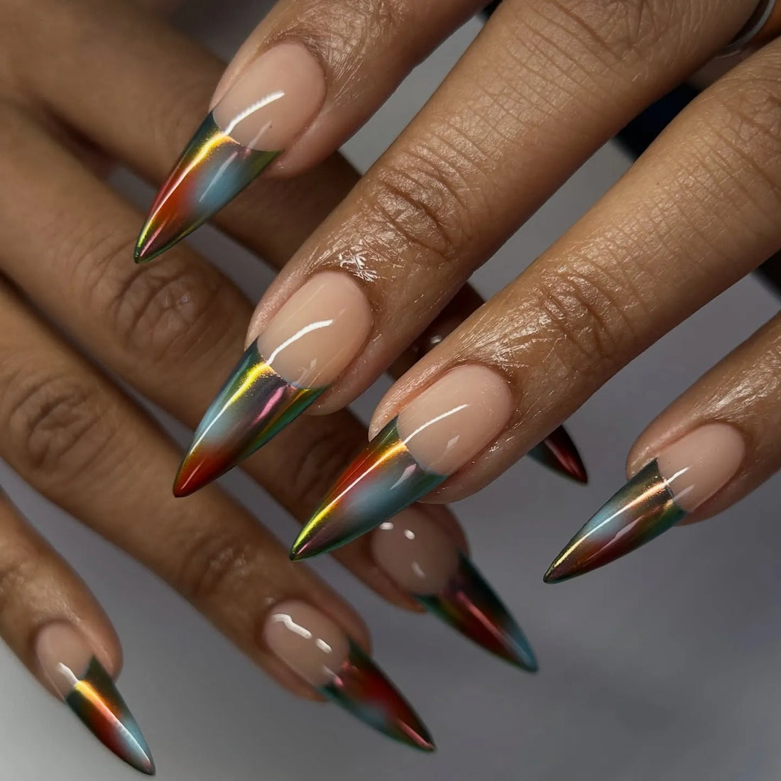 Hand with extra long stiletto press-on nails, multicolor chrome French tip design