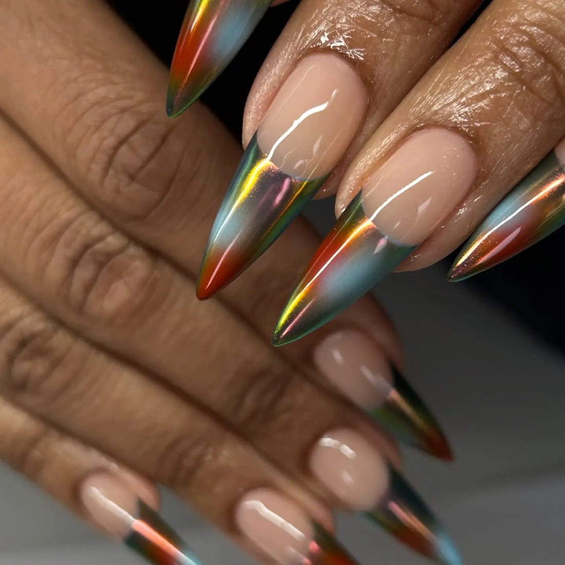 Hand with extra long stiletto press-on nails, multicolor chrome French tip design