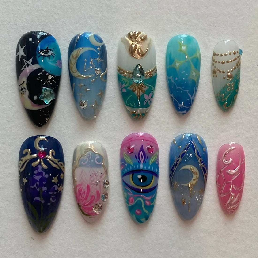 Handmade blue and gold celestial themed press-on nails with mystical eye and moon designs