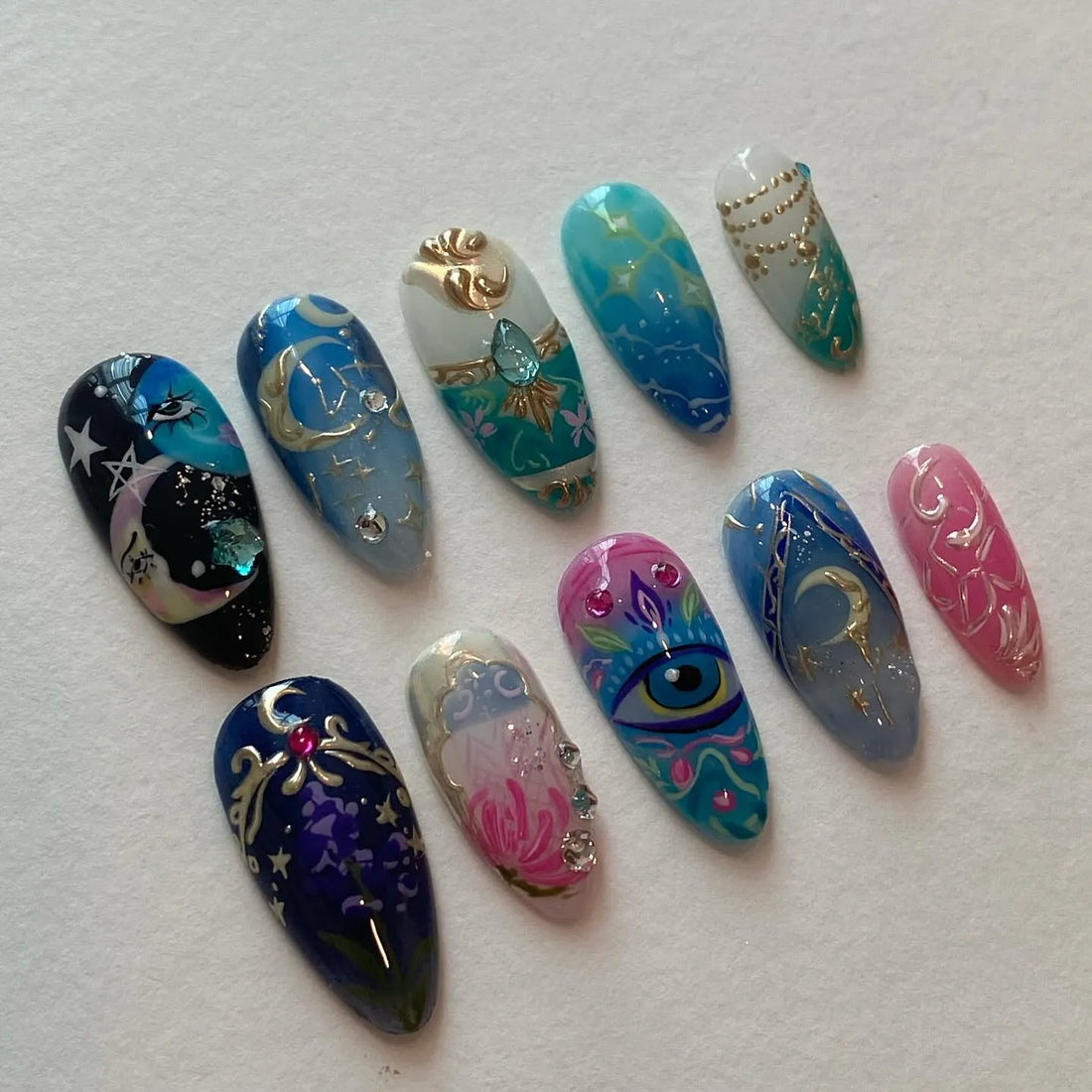 Handmade blue and gold celestial themed press-on nails with mystical eye and moon designs