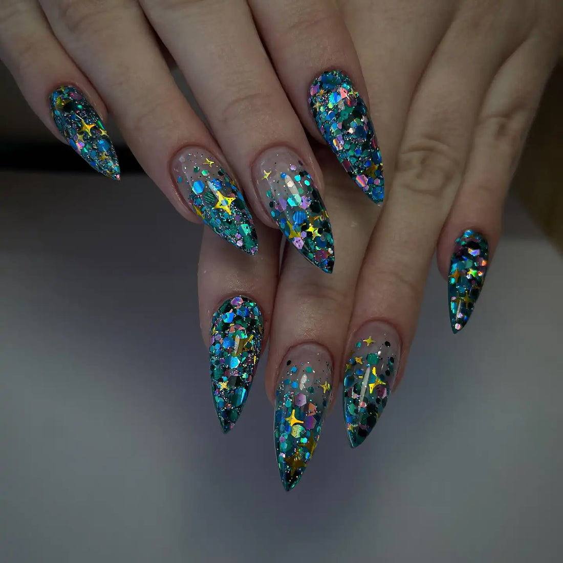 Handmade teal galaxy press-on nails with chunky star glitter and stiletto shape