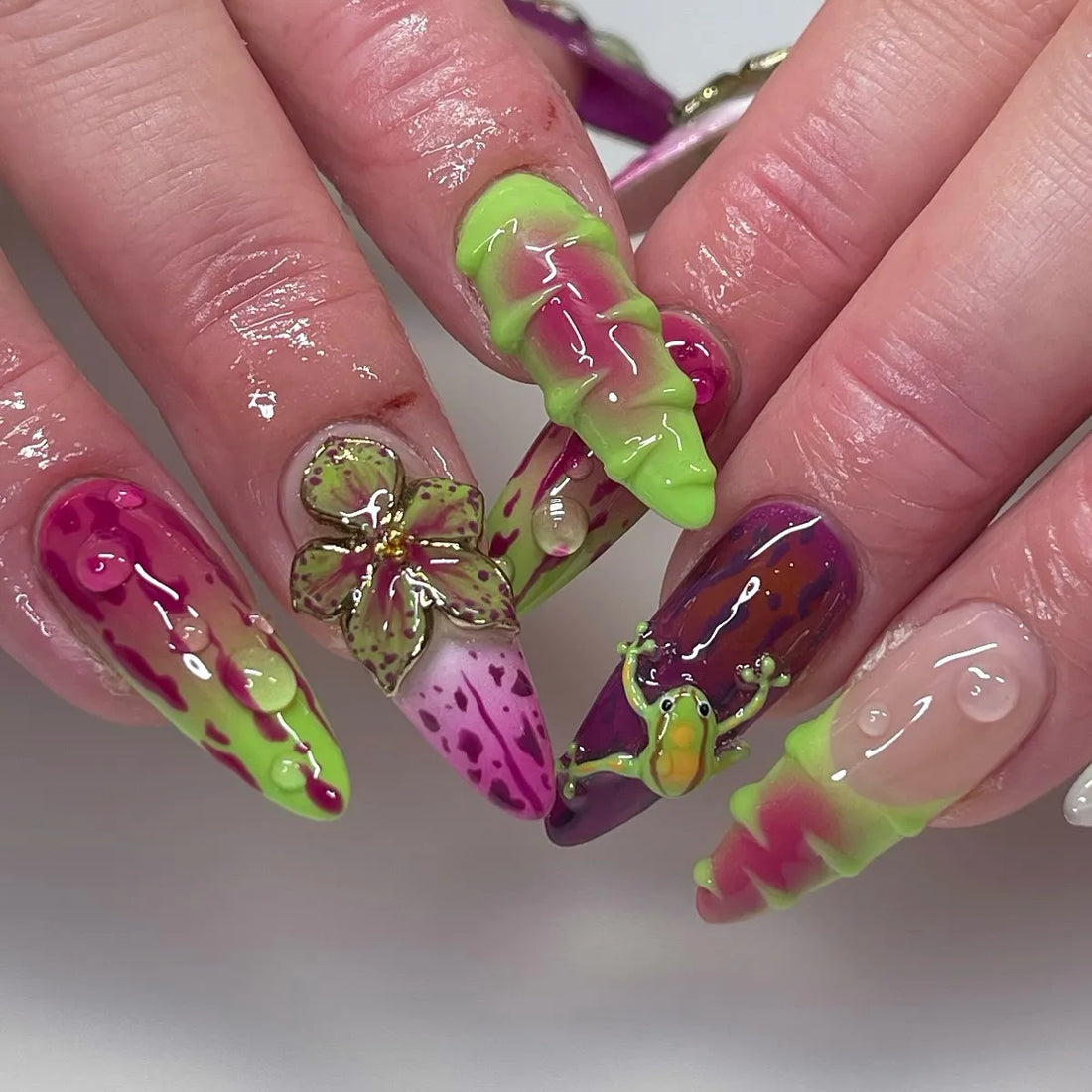 Handmade neon green, pink, and purple press-on nails with abstract drip and frog designs.