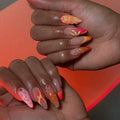 Hand with handmade neon orange and pink mismatched butterfly abstract summer press-on nails.