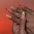 Hand with handmade neon orange and pink mismatched butterfly summer press-on nails.