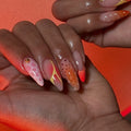 Hand with handmade mismatched neon orange and pink abstract summer press-on nails