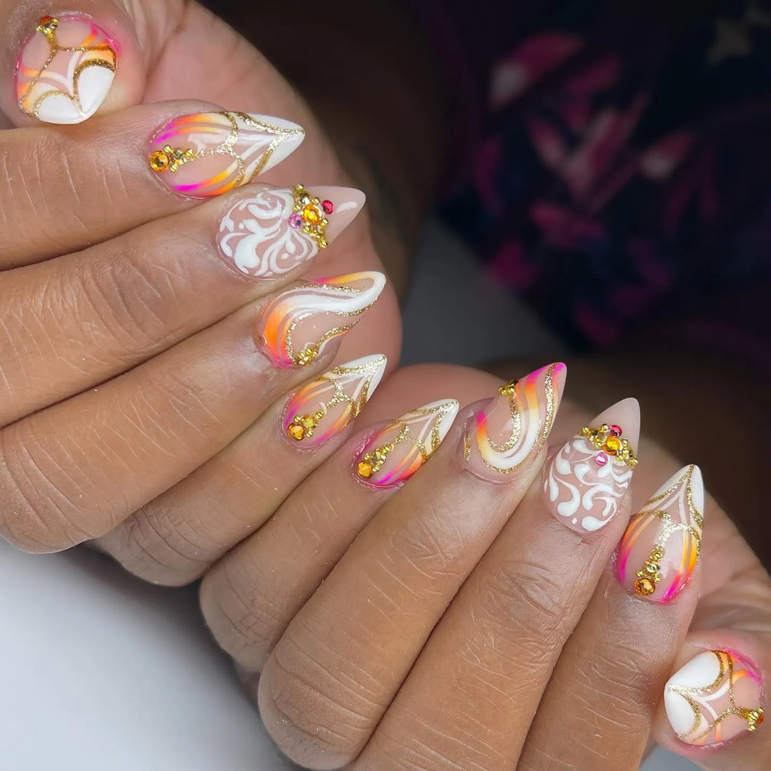 Handmade press-on nails with neon sunset colors, gold swirl accents, rhinestones, and white detailing