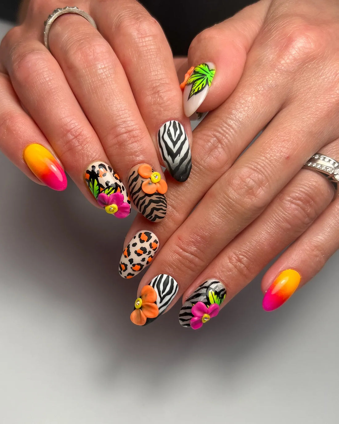 Handmade press-on nails with zebra and leopard prints, neon florals, and tropical leaf designs.