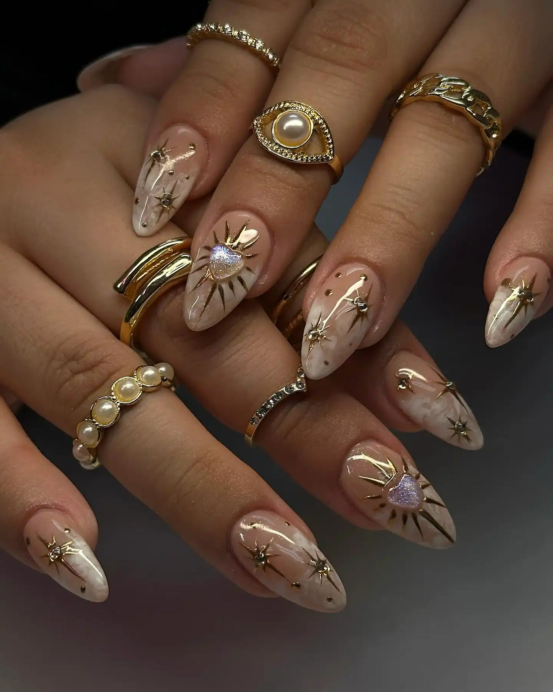 Handmade nude press-on nails with gold celestial heart charms and soft smoke art design