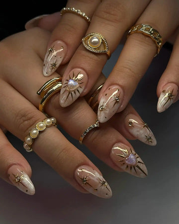 Handmade nude press-on nails with gold celestial heart charms and soft smoke art design