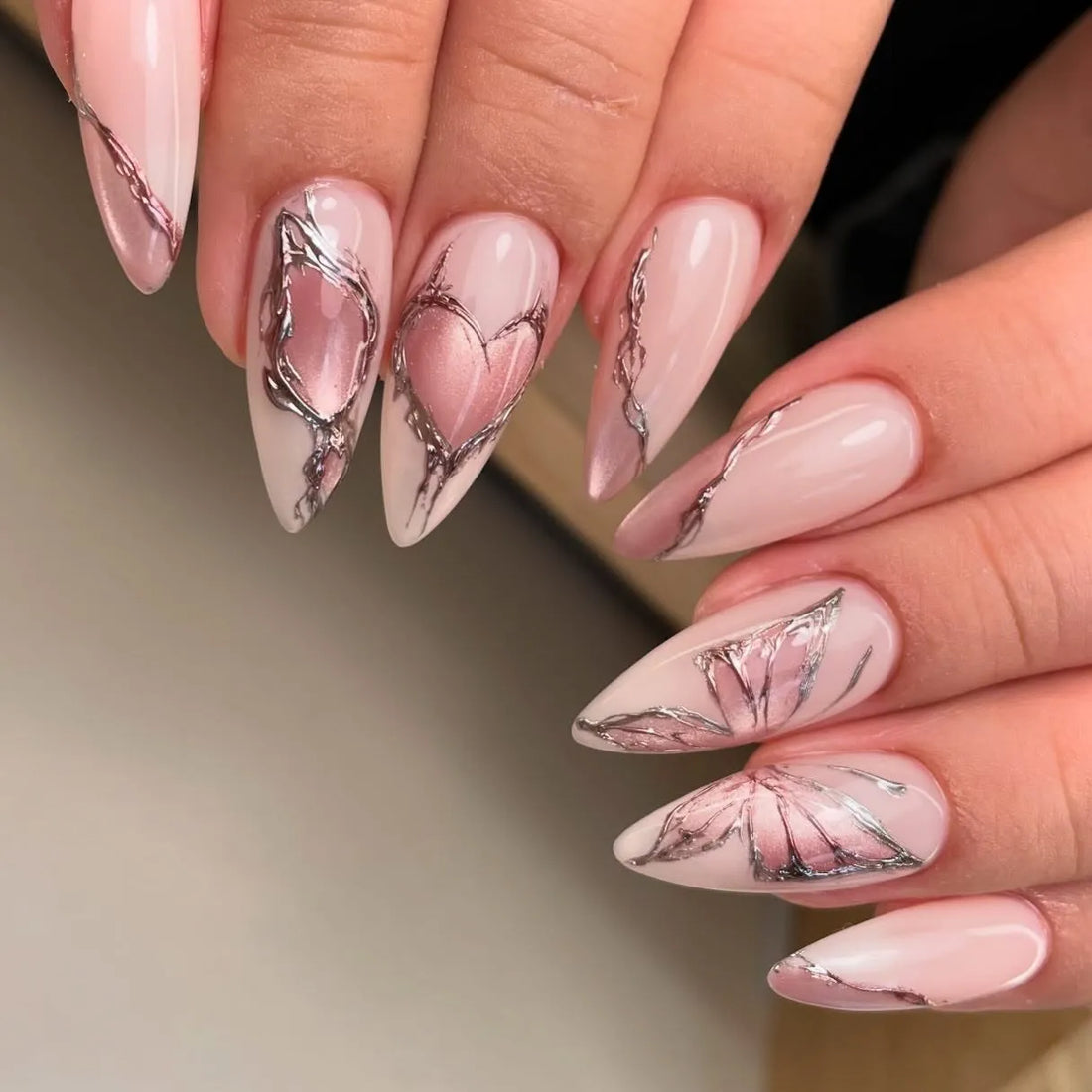 Handmade nude pink chrome press-on nails with silver heart and butterfly designs