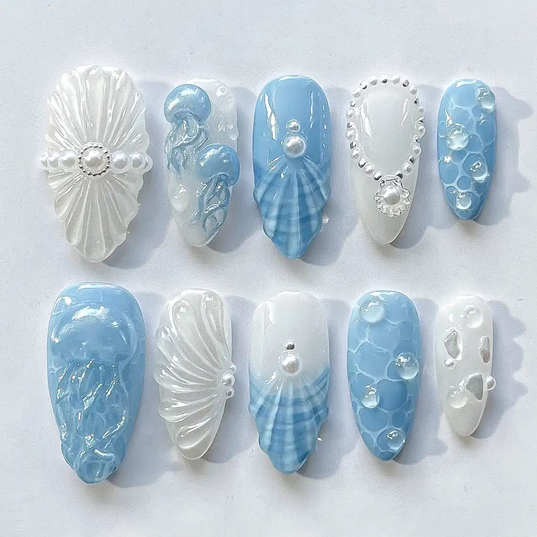 Handmade press-on nails with ocean blue and white jellyfish, pearl, and seashell designs.