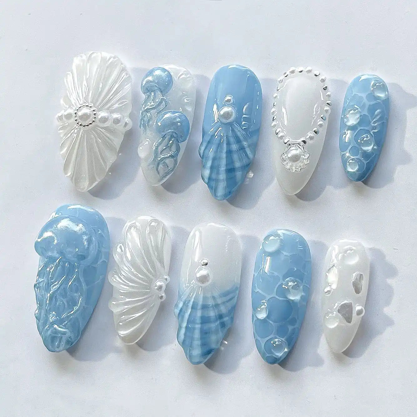 Handmade blue and white press-on nails with jellyfish, seashell, and pearl ocean designs.