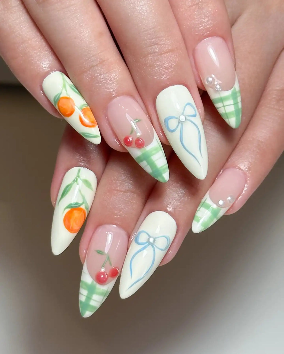 Handmade press-on nails with orange, cherry, ribbon art and green plaid details