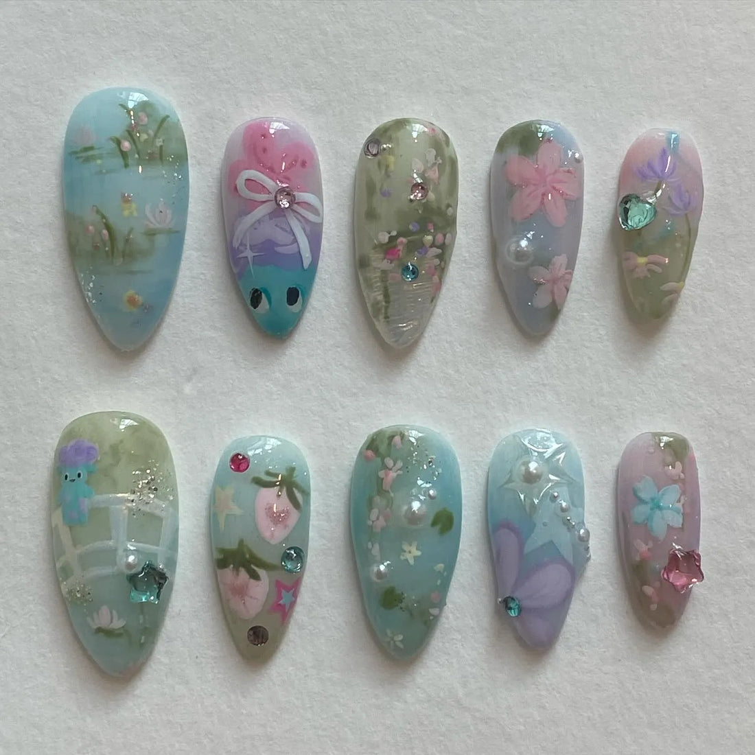Handmade pastel press-on nails with whimsical floral and butterfly designs, fairy garden theme.