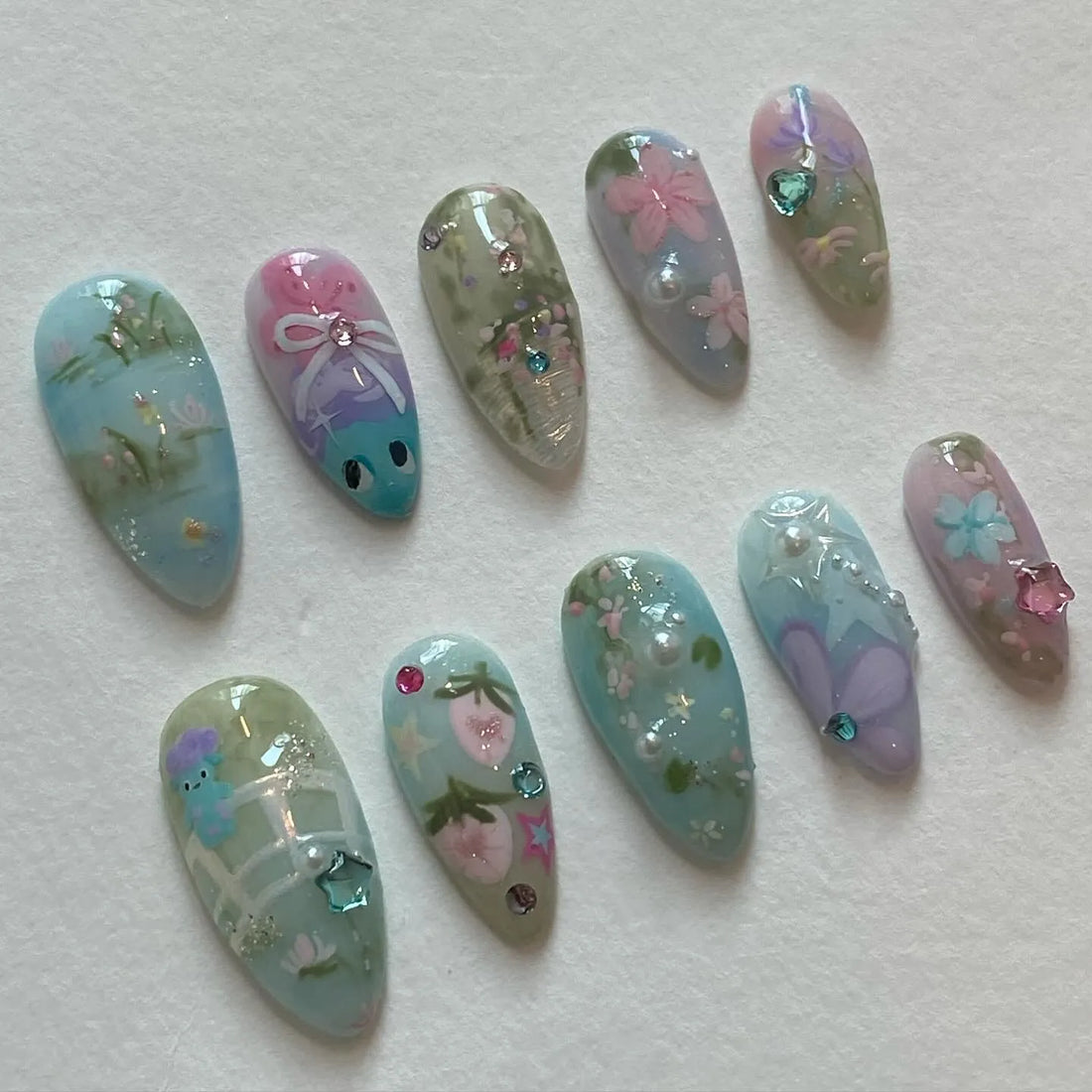 Handmade pastel press-on nails with whimsical floral and butterfly designs, fairy garden theme.