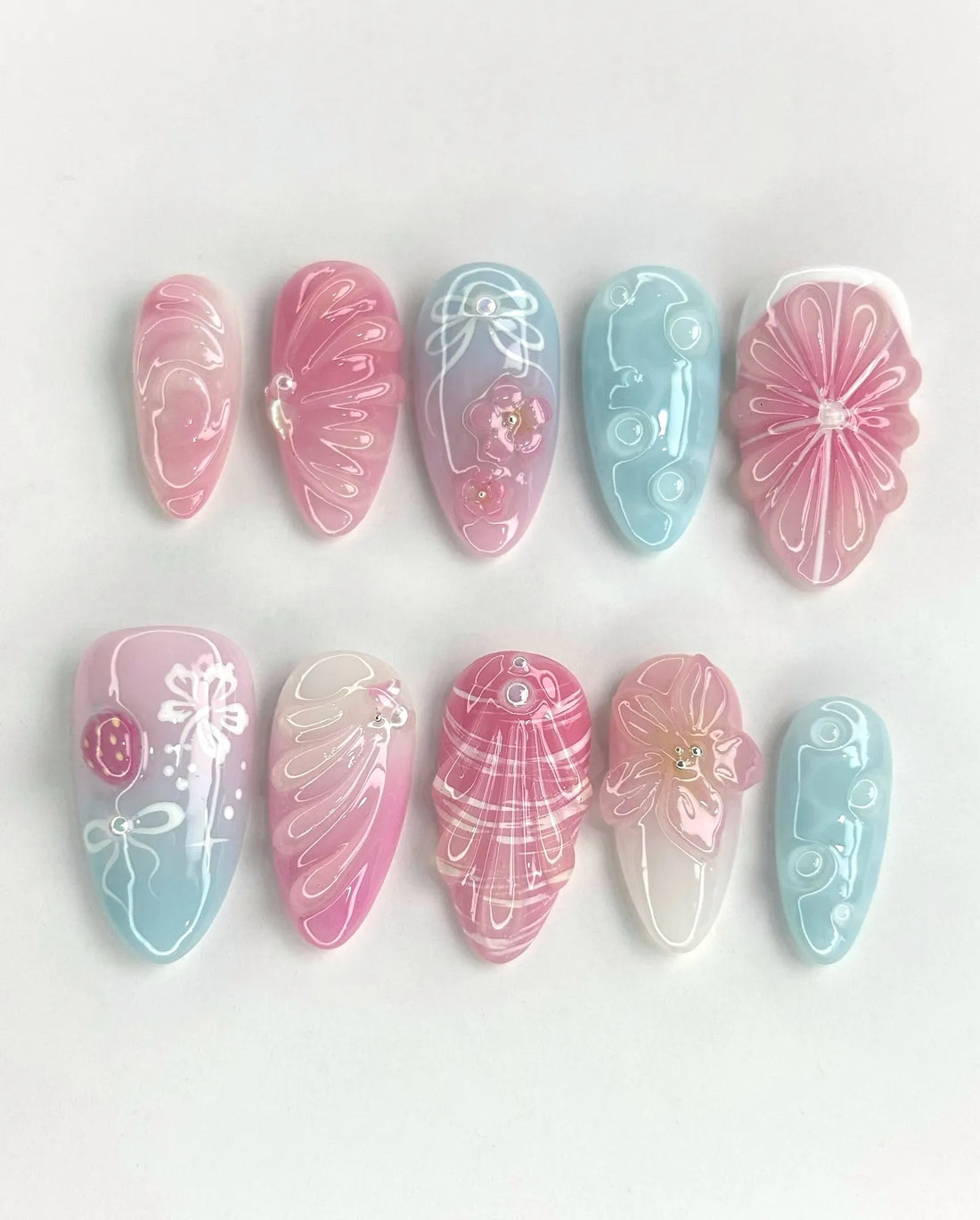Handmade pastel pink and blue 3D floral sculpted shell press-on nails with glossy finish.