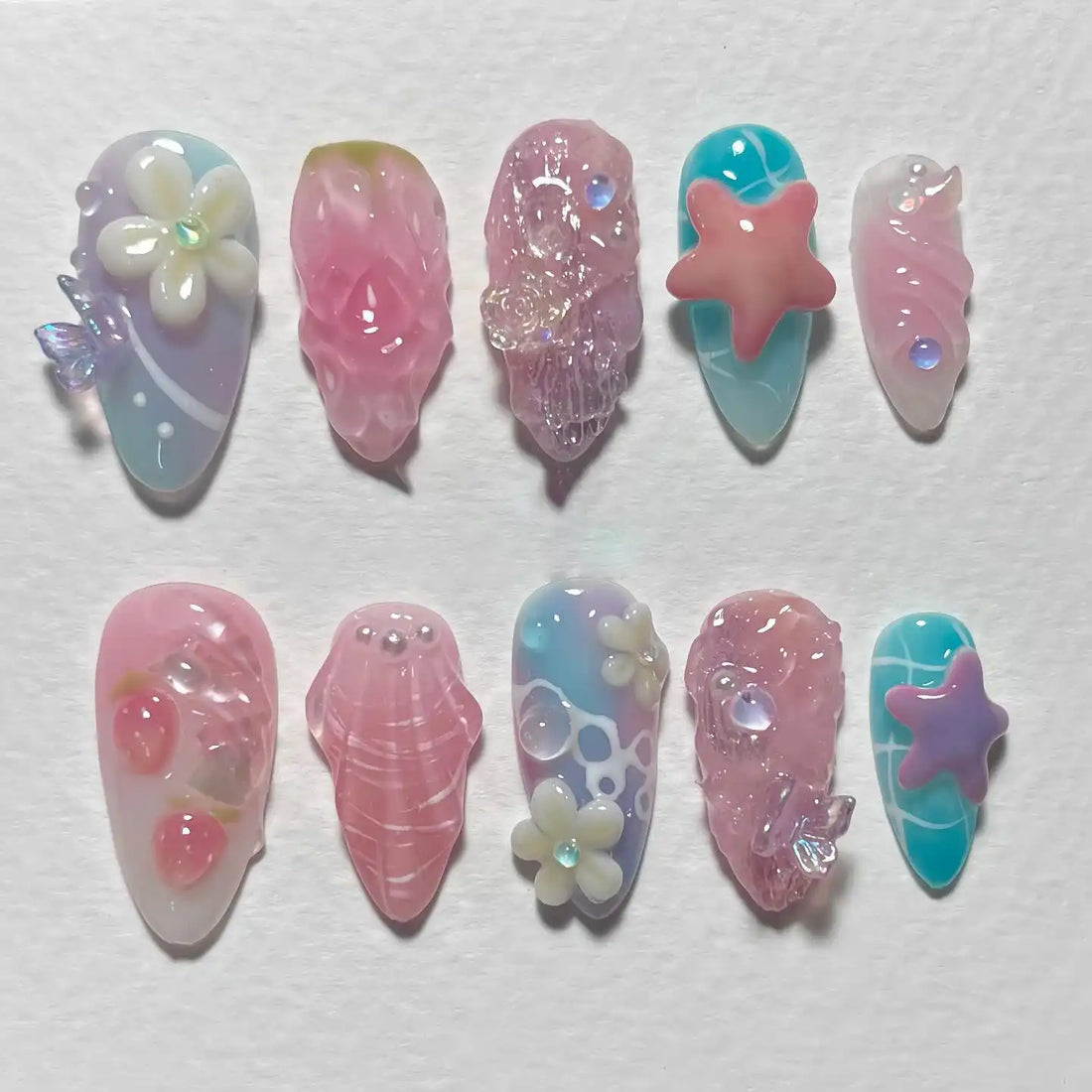 Handmade pastel press-on nails with seashell, starfish, and flower ocean-themed designs.
