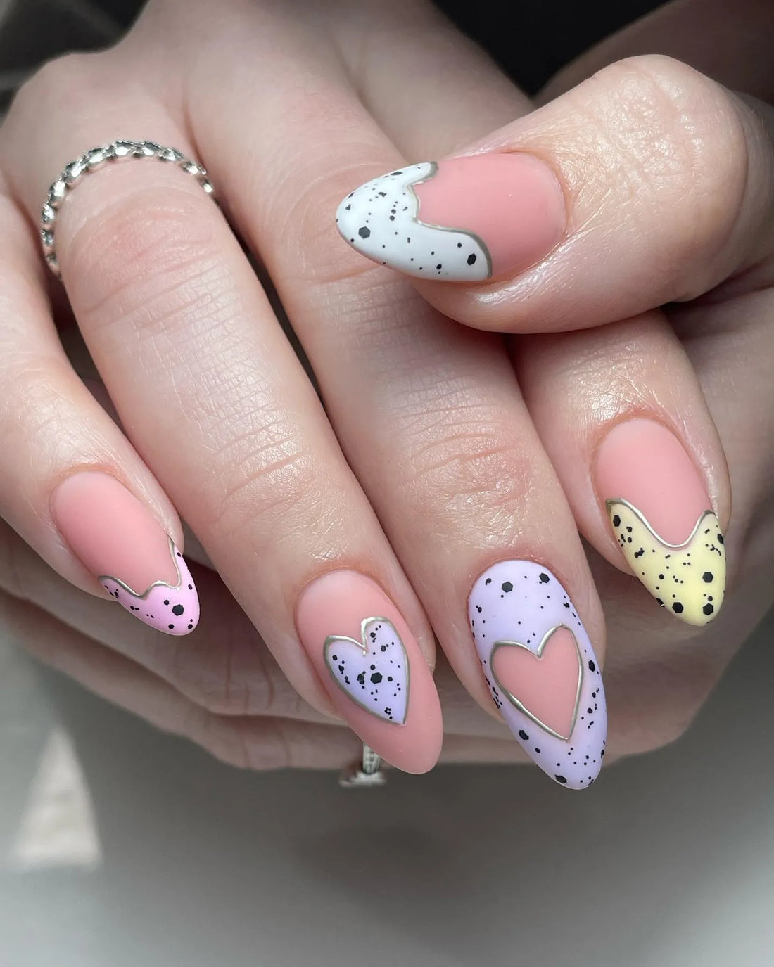 Handmade pastel press-on nails with speckled heart designs and silver outlines