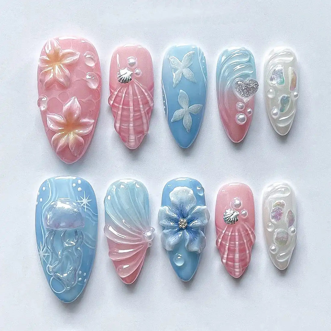 Handmade pink and blue press-on nails with seashell, jellyfish, floral, and mermaid designs.