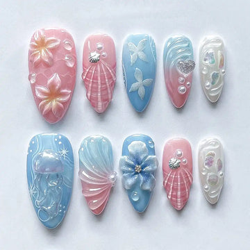 Handmade pink and blue press-on nails with seashell, jellyfish, floral, and mermaid designs.