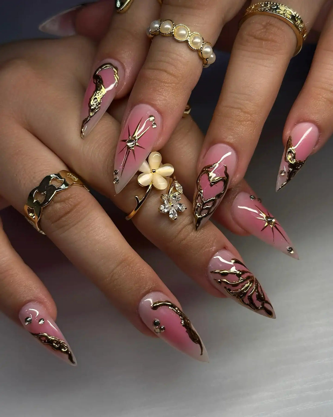 Handmade pink press-on nails with chrome heart and star designs, gold accents, and rhinestones.
