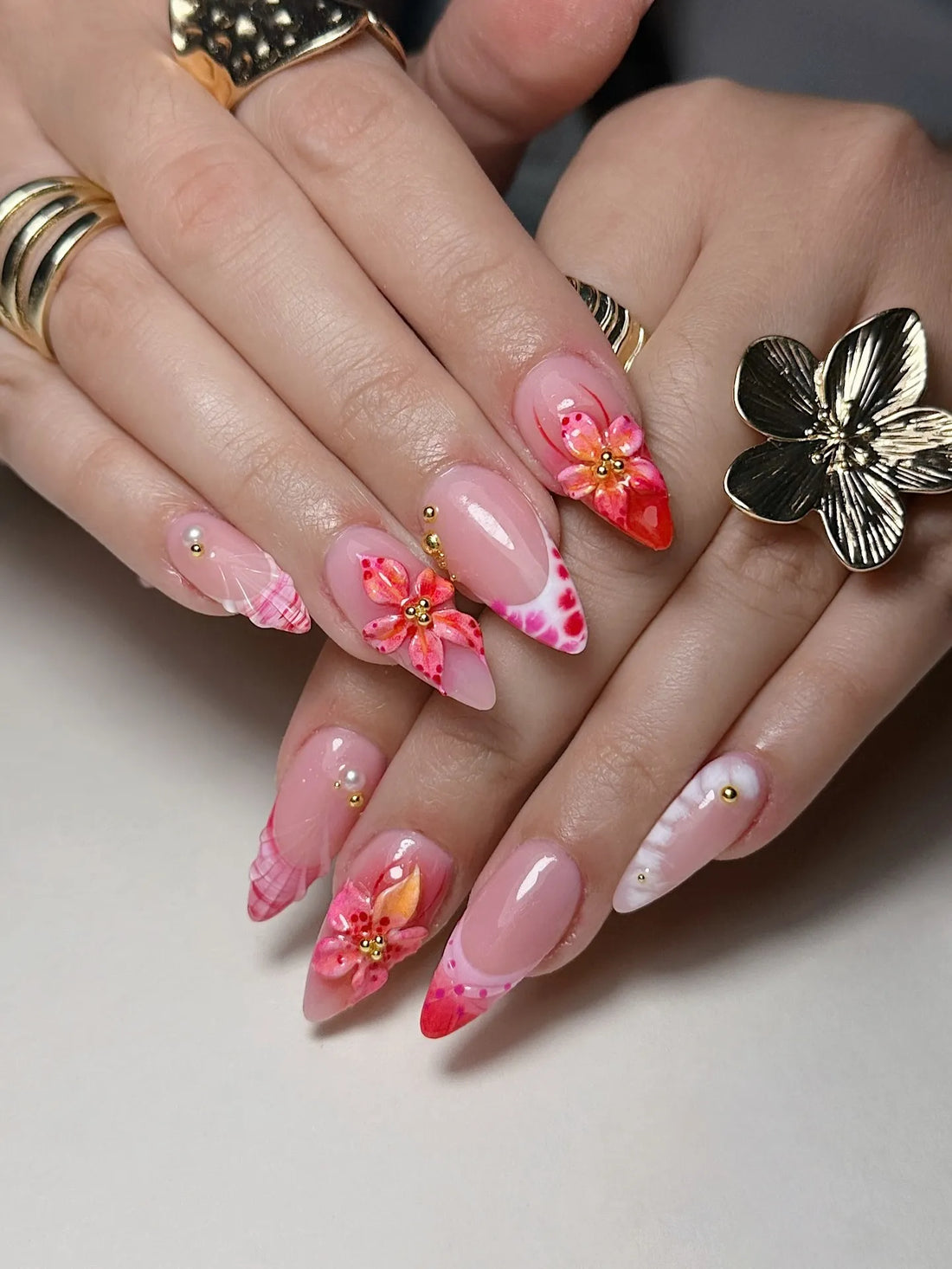 Hand with handmade pink 3D hibiscus floral, seashell, and French tip press-on nails