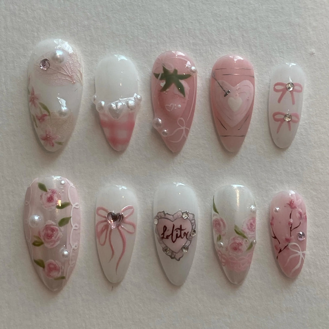 Handmade pink Lolita press-on nails with roses, bows, pearls, hearts, and gingham designs.