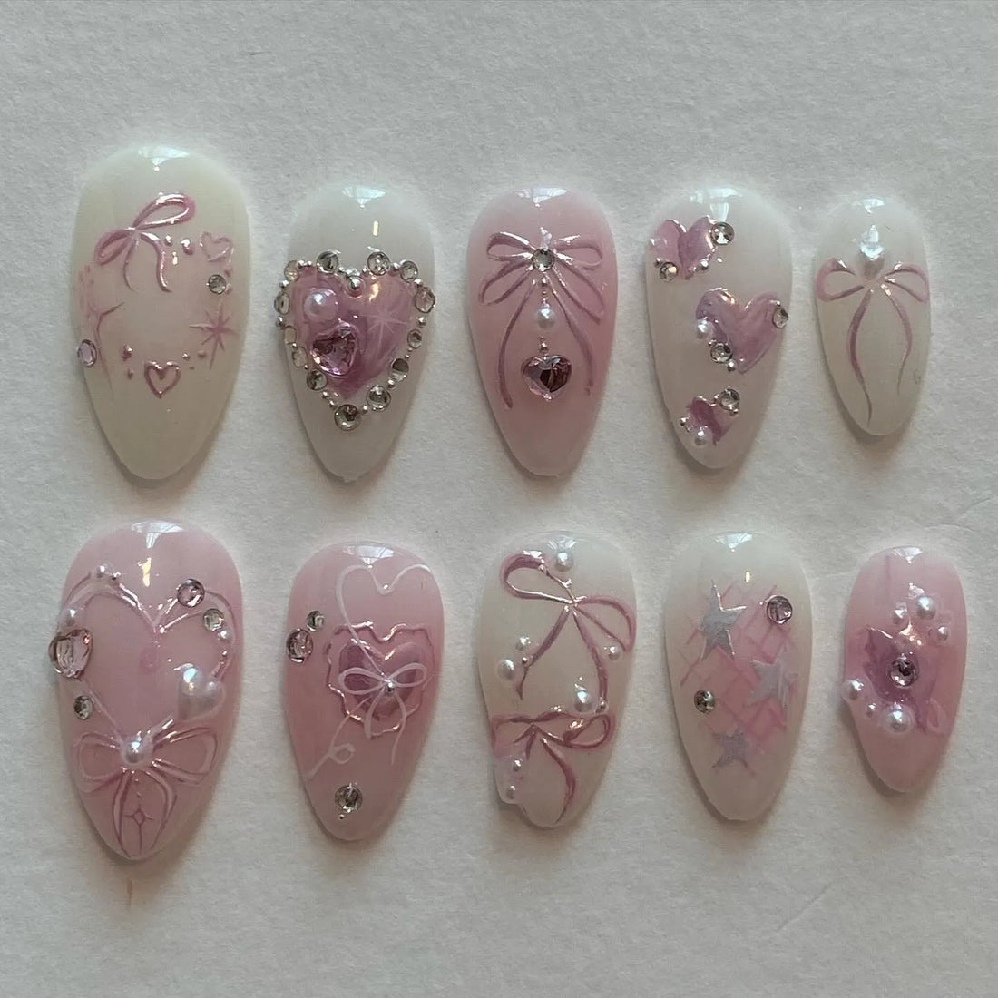 Handmade pink heart charm press-on nails with bow, crystal, and pearl accents, reusable set