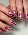 Handmade pink metallic chrome press-on nails with heart and folk art patterns.