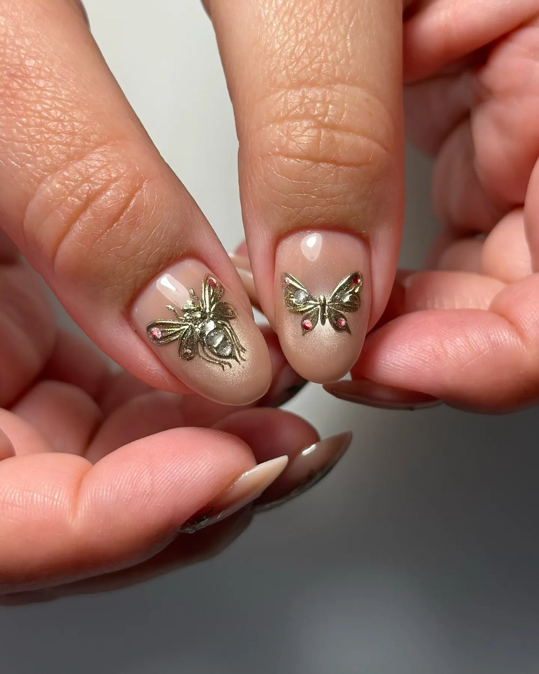 Handmade pink nude press-on nails with gold insect, dragonfly, rose, and gemstone accents