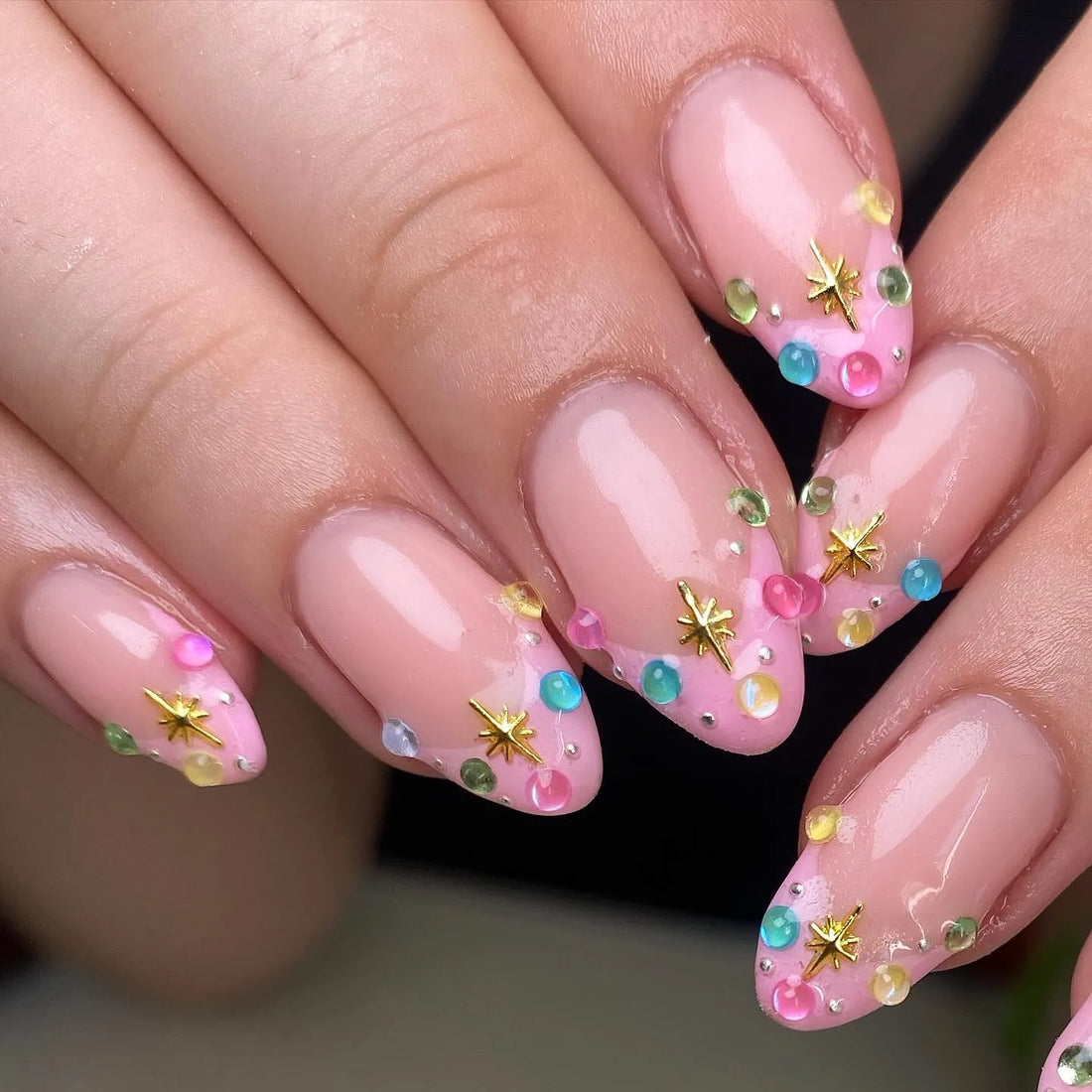 Handmade pink pastel press-on nails with gold star accents and colorful gemstone tips