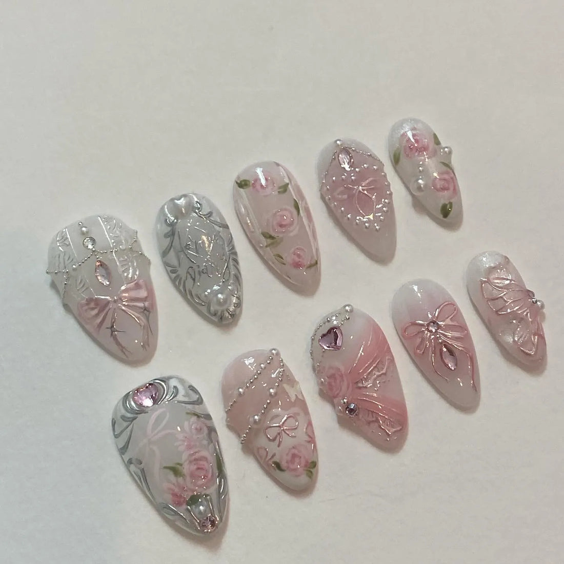 Handmade press-on nails with pink rose designs, silver baroque details, bows, and pearl chains