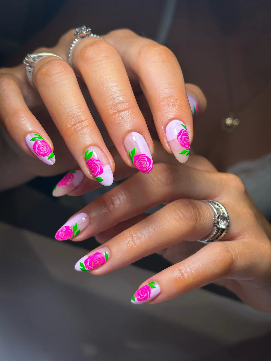 Hand-painted press-on nails with pink rose designs and green leaves on French tips