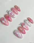 Handmade pink and white press-on nails with swan, bows, glitter, jewels, and 3D detailing.