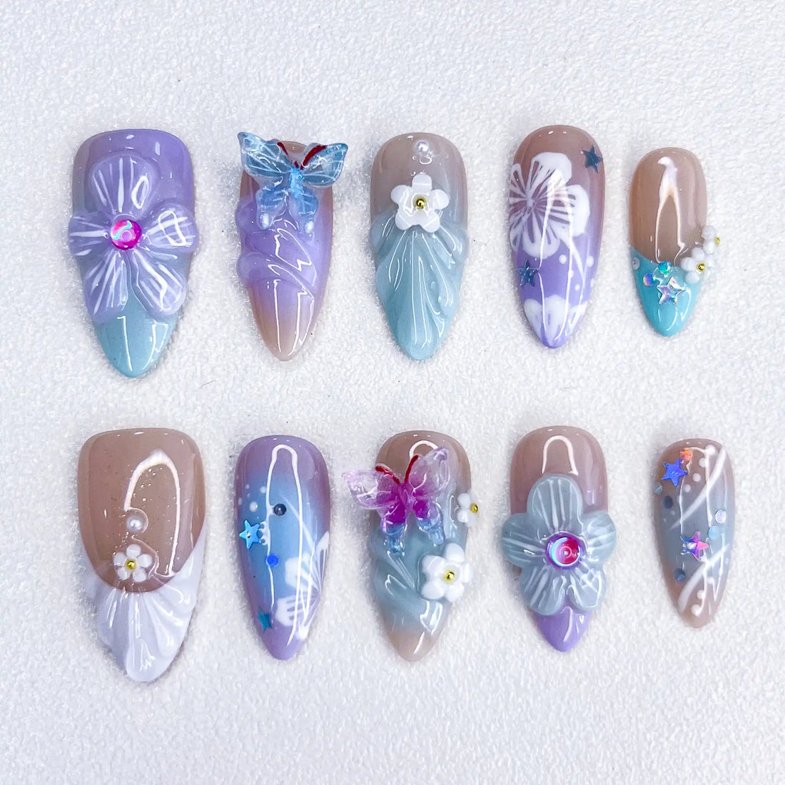 Handmade pastel press-on nails with purple butterfly, floral accents, and sparkle details