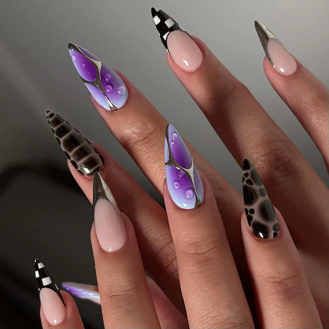 Handmade press-on nails with purple gradient, metallic accents, and geometric designs